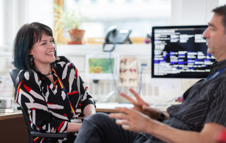 Two staff  members sitting down and talking in a meeting