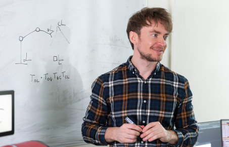 researcher stood in front of a wipe-board smiling at a person off-camera