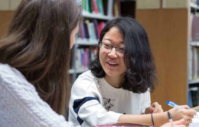 two people sat in a library talking to each other