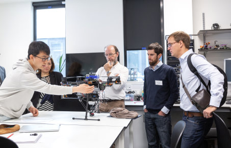 male student showcasing his project to a group of four people