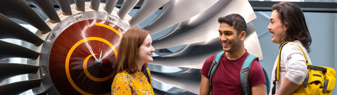 Undergraduate students and Imperial Outreach student mentors stand and chat in the City and Guilds building foyer