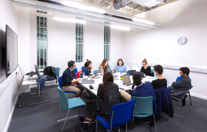group of people sitting round a table working on computers