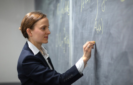 A student writes equations on a chalkboard