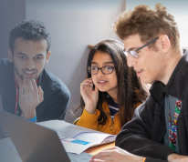 Three students working at a laptop