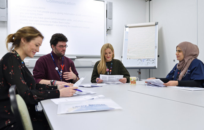 four people sitting round a table looking at papers