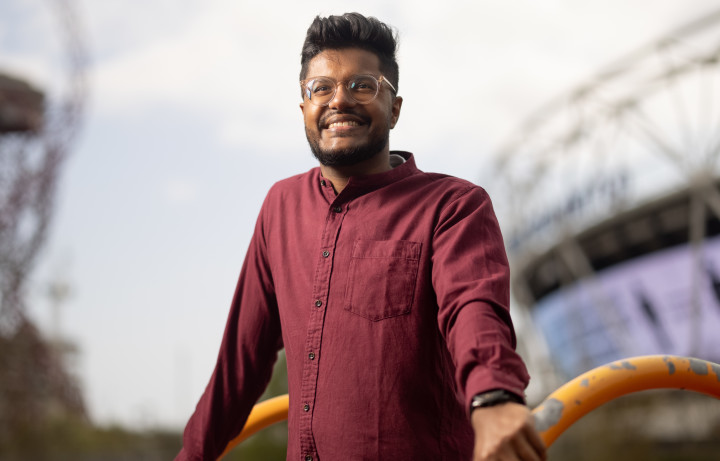Rokshan smiles, standing in traditional attire in Queen Elizabeth Olympic Park