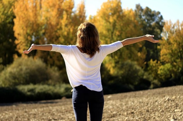 Lady with arms spread in front of trees