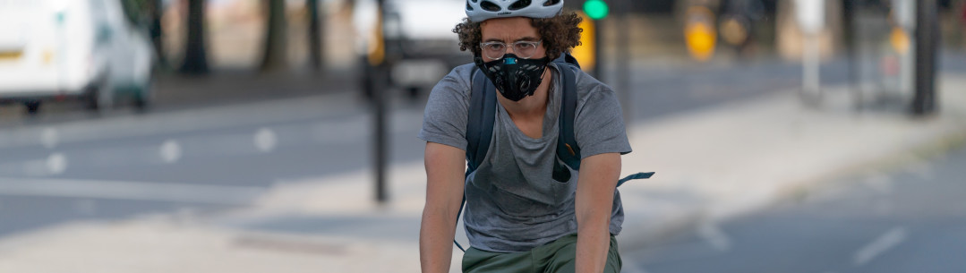 LONDON, ENGLAND - MAY 27, 2020: Young adult man riding on a bicyle in a commuter cycle lane along the Embankment next to the Thames River in Central London, England