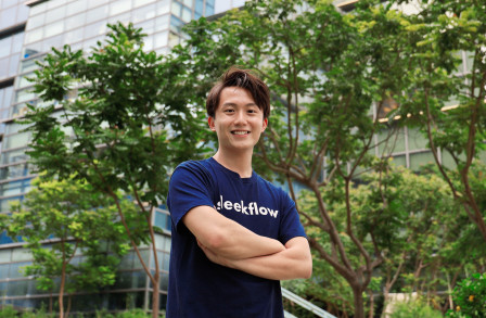 Henson Tsai standing with arms folded against backdrop of a building and trees