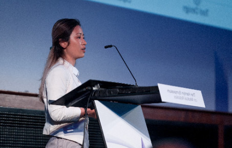 A woman presenting from a lectern