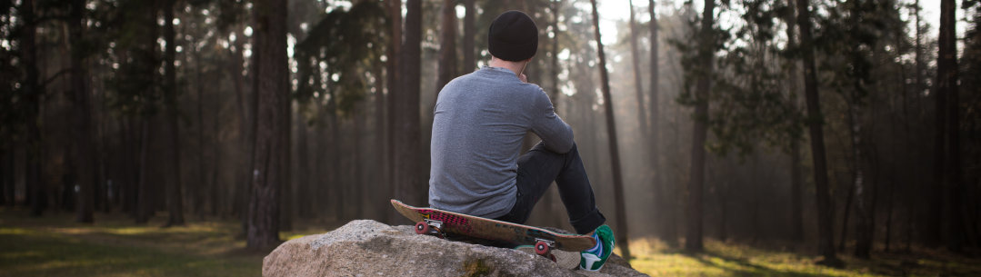 A young man sat on a rock with his back to the camera