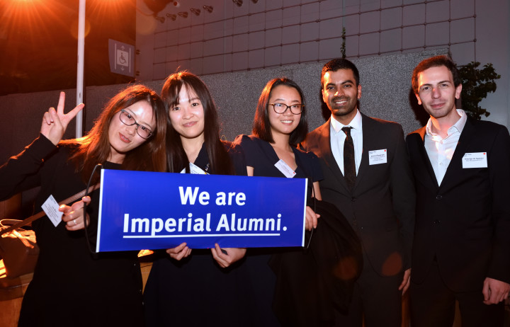 A group of alumni smiling at the camera, holding a banner that reads 'We are Imperial alumni'