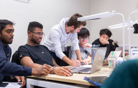 Students gathered round a desk with laptops