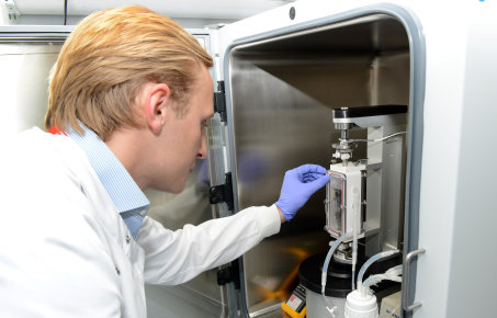 researcher leans in to use equipment in cabinet