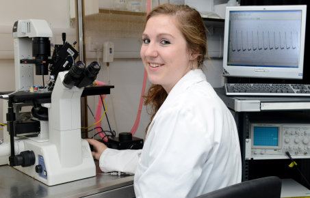 researcher sits by microscope
