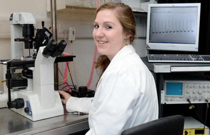 Female researcher looks back from microscope