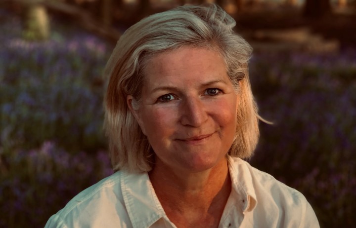 Head-shot of Lucy Carmody, a white woman with blonde bob haircut wearing a light coloured open silk blouse, she has fair skin and is smiling.
