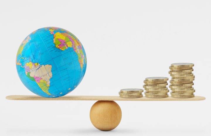 Globe and pile of coins on a balance scale